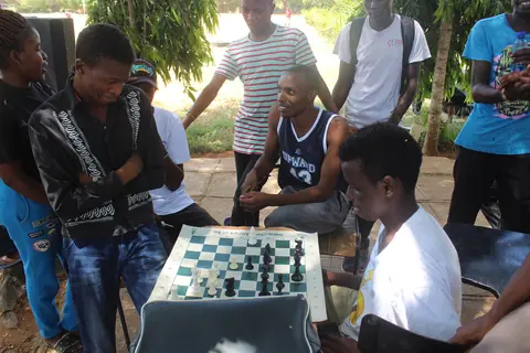 A group gathered around an outdoor chess game