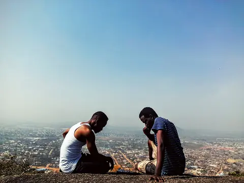 Two players at a chess game on a hilltop overlooking a city